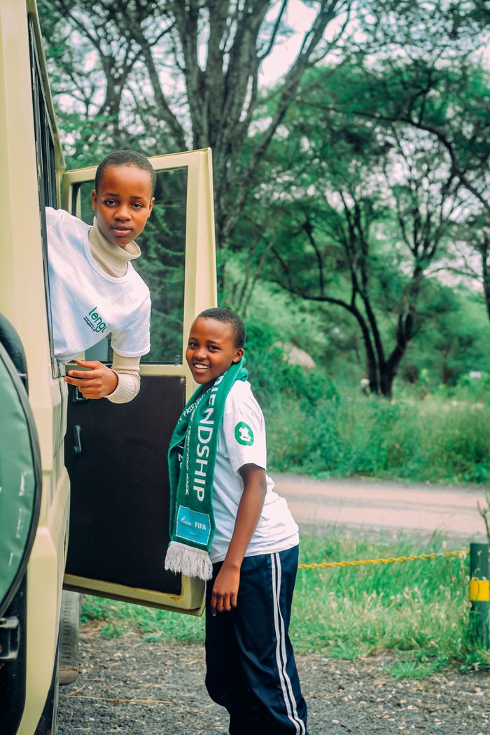 Two children in safari clothing smiling and exploring the outdoors from a vehicle.